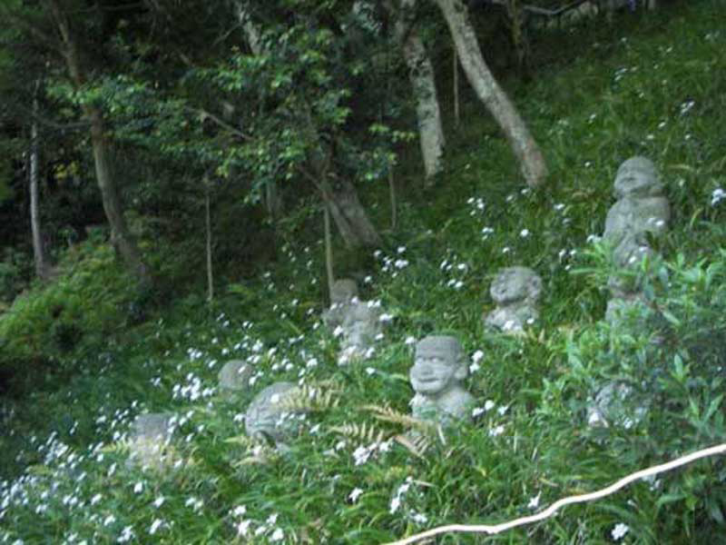 small statues in overgrown grass