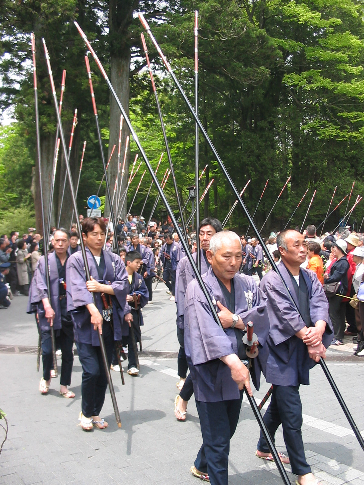men in tradtional garb holding tall black poles