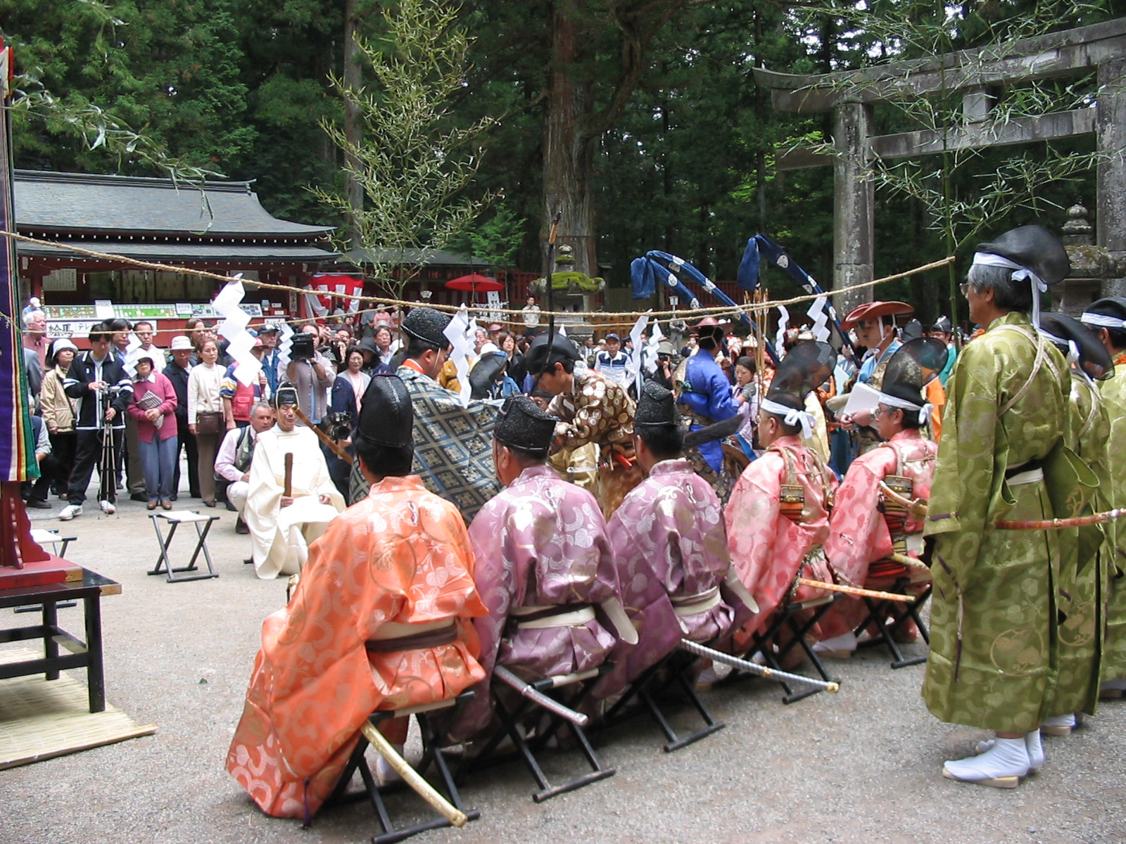 men standing and sitting while wearing traditional garb and watching man give speech