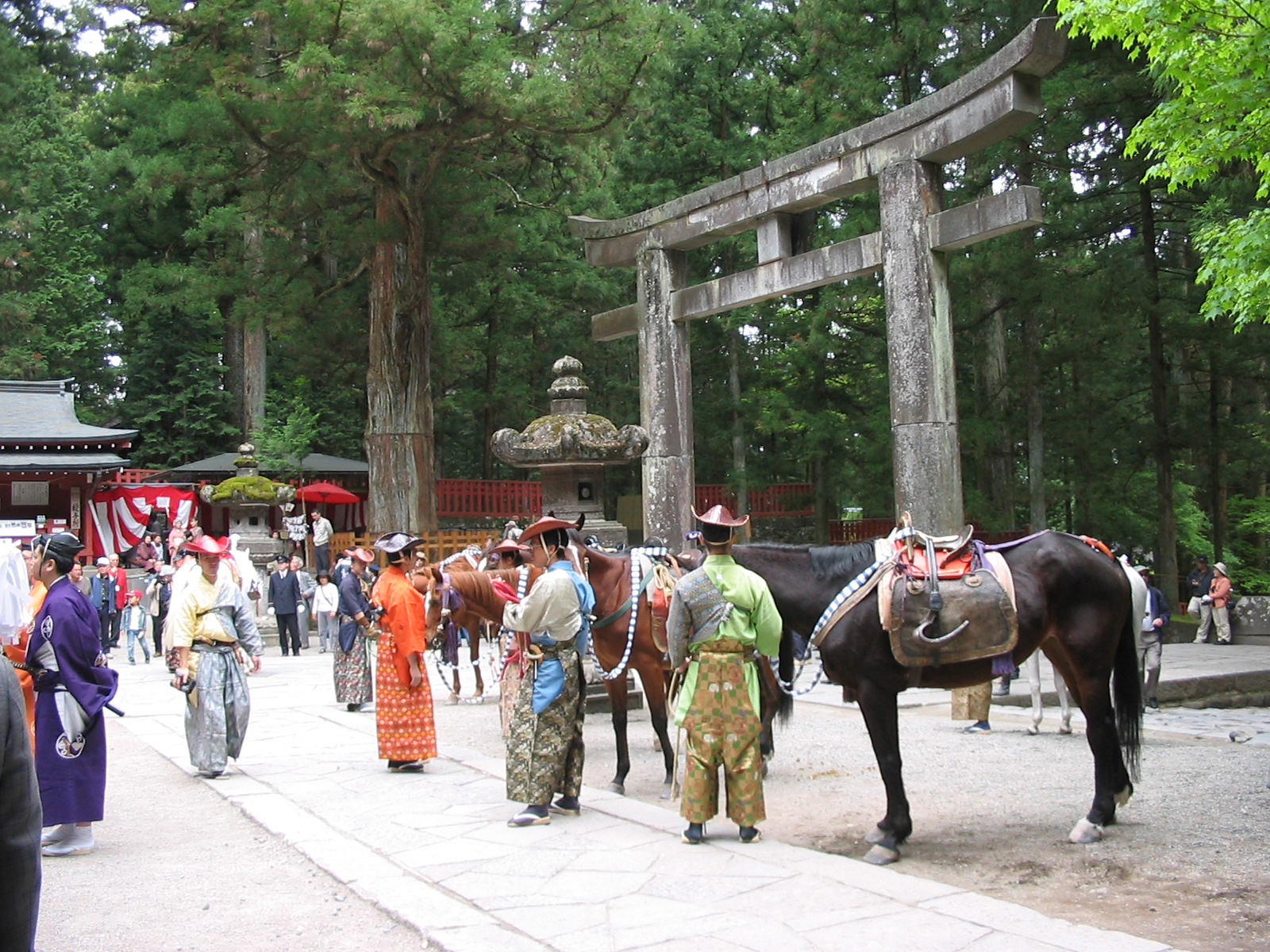 men in traditional clothing standing with a horse in front of a torri gate