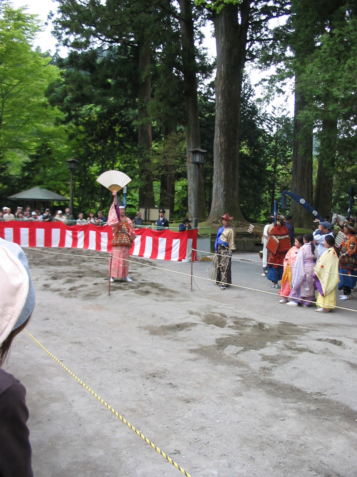 man raising fan above head at the start of the horse track