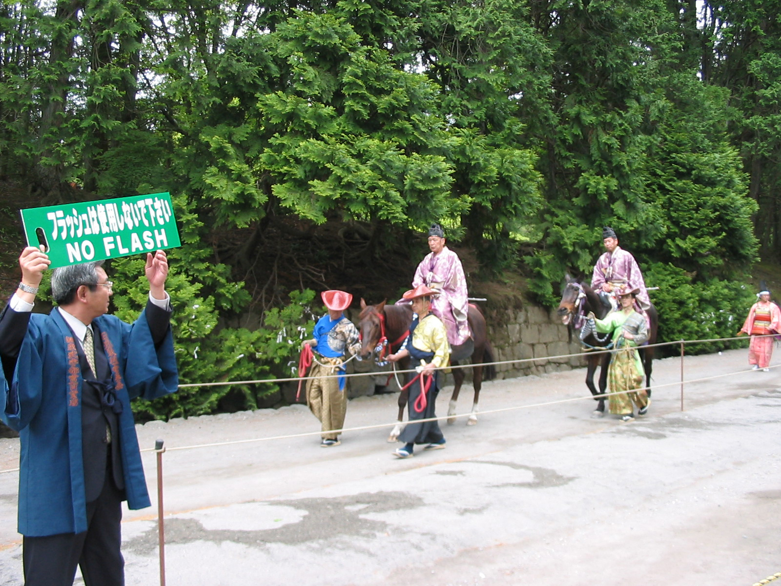 view from the horse track with men walking horses to the start of the track and man holding a sign saying 'no flash'