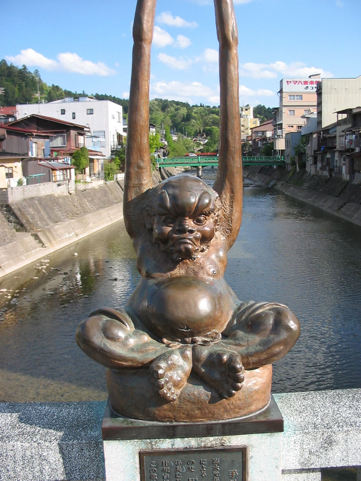 anatomically correct statue of a short male with a round belly and his arms raised up