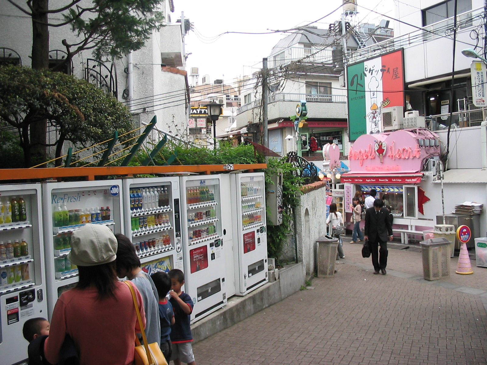 sidewalk with line of vending machines and store with large pink sign